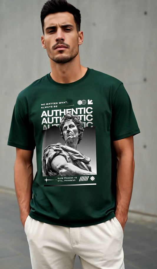 Man wearing a green t-shirt with graphic design and text against a gray wall.