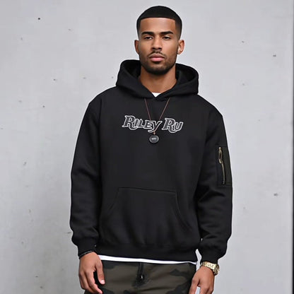 Man wearing a black hoodie with text and camouflage pants against a gray background