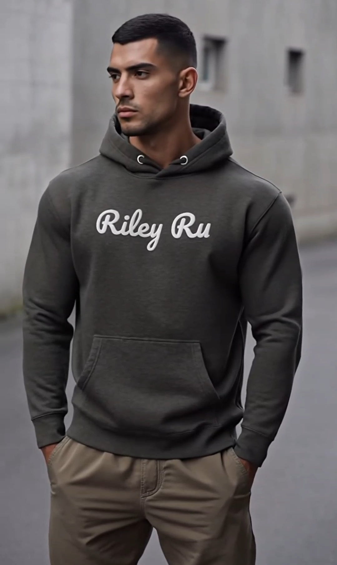 Man wearing a dark gray hoodie with 'Riley Ru' text, standing on a street.