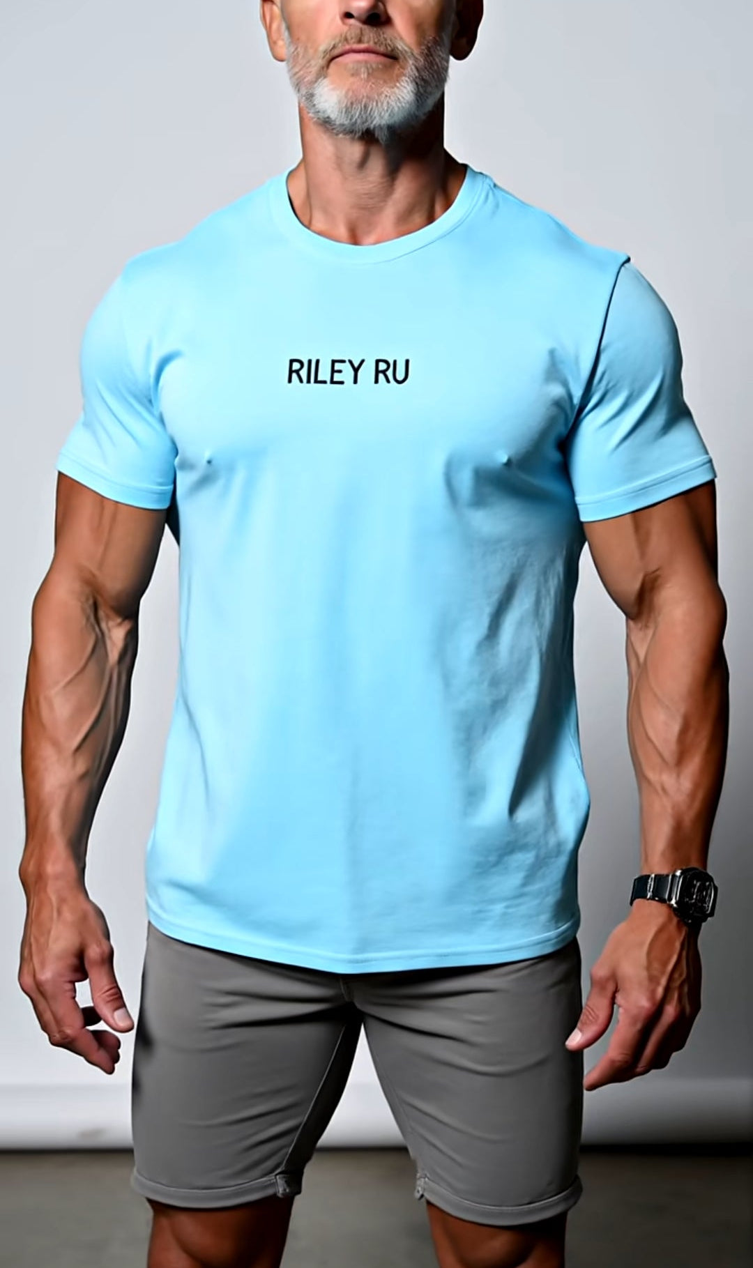 Man wearing a light blue t-shirt with 'RILEY RU' branding and gray shorts against a plain background.
