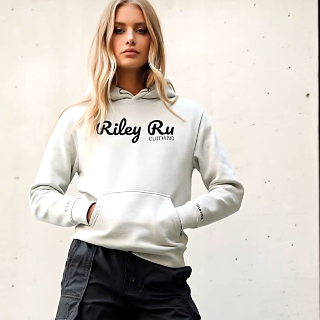 Person wearing a white hoodie with 'Riley Ru' branding, black cargo pants, and black boots against a light background.