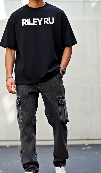 Person wearing a black t-shirt with 'RILEYRU' text and dark cargo pants against a plain background