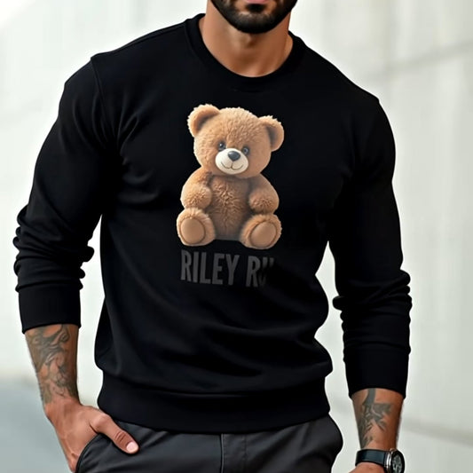 Man wearing a black sweatshirt with a teddy bear graphic and text, standing against a light background.