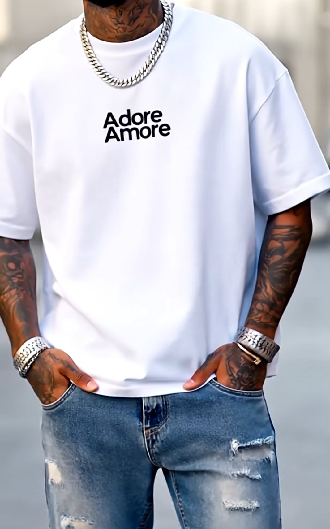 Person wearing a white t-shirt with 'Adore Amore' text, blue jeans, and jewelry.