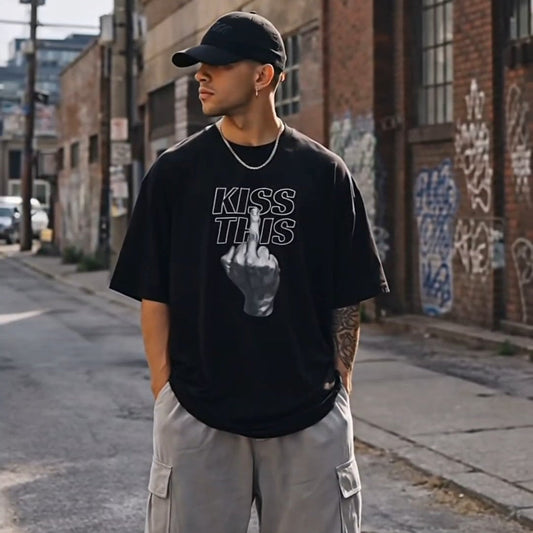 Person wearing a black t-shirt with text and graphics, gray cargo pants, and black sneakers on an urban street.