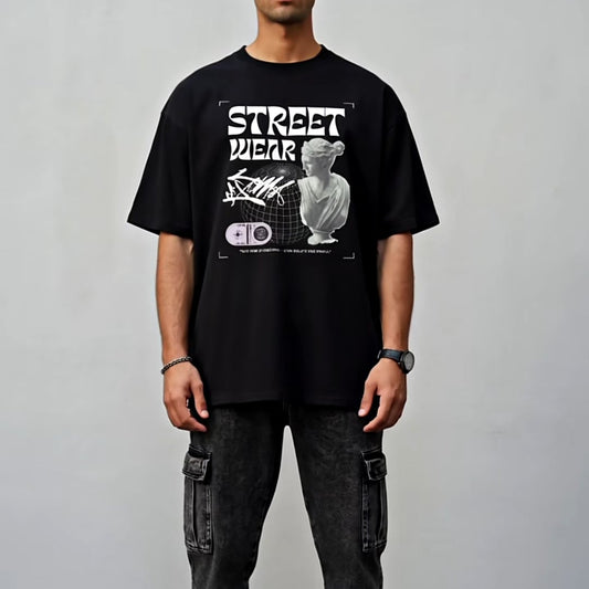 Person wearing a black t-shirt with graphic design and text, standing against a plain background