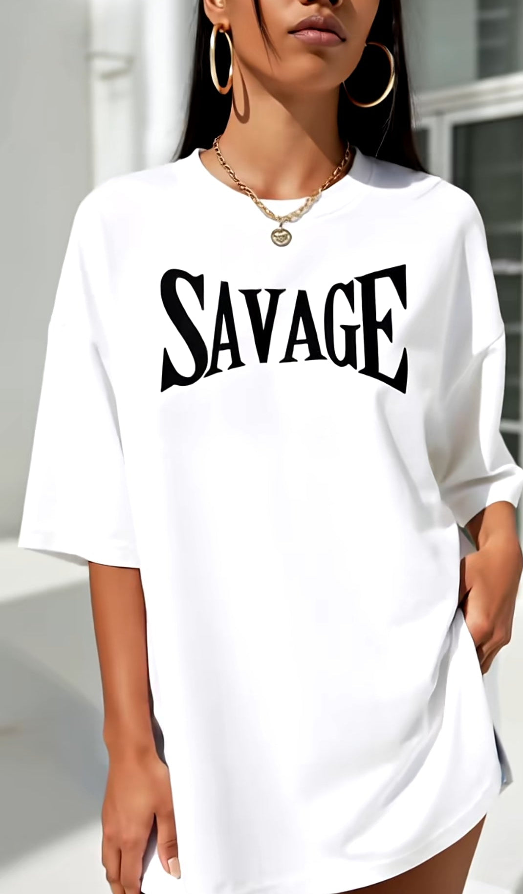 Person wearing a white t-shirt with 'SAVAGE' printed on it, standing outdoors.