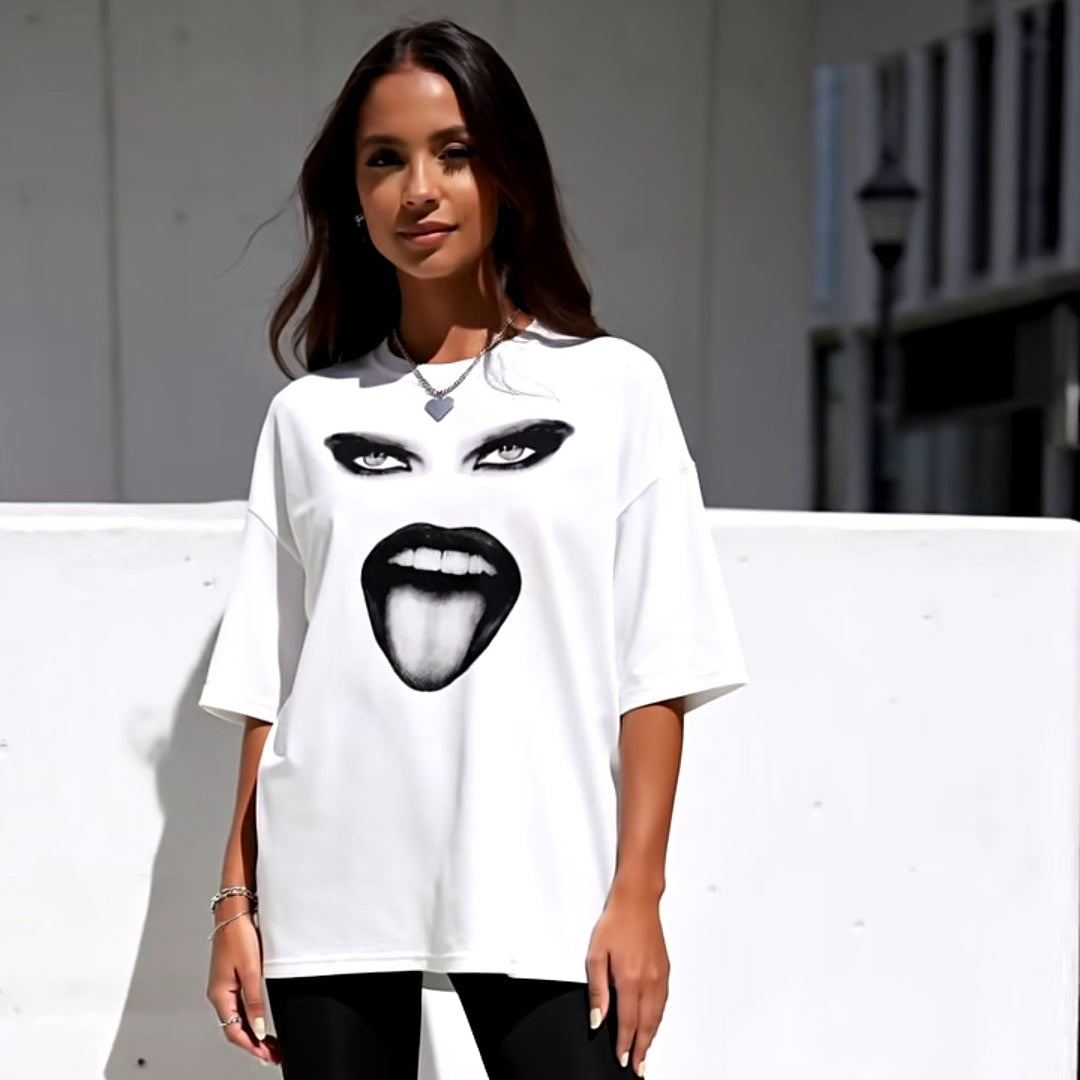 Person wearing a white t-shirt with a graphic design, black shorts, and white sneakers on a light background.