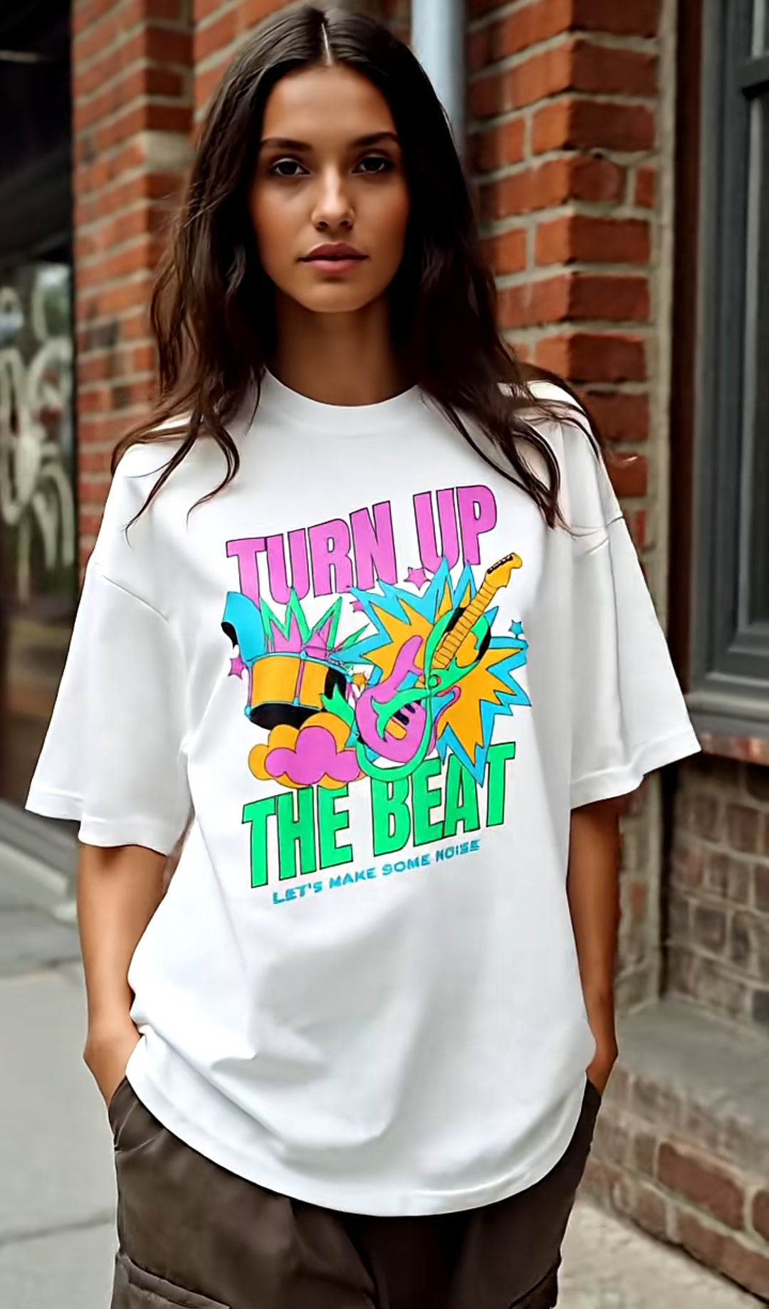 Person wearing a white t-shirt with colorful text and graphics on a brick wall background