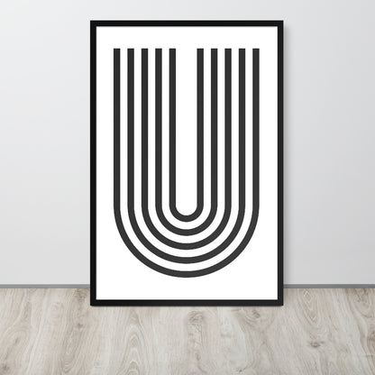 Framed abstract art print with black U-shaped lines on a white background, placed on a wooden floor.