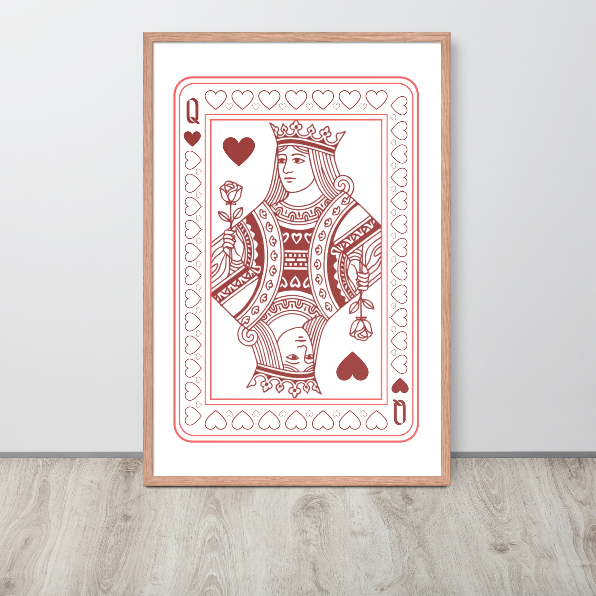 Framed playing card print of a queen with hearts on a white wall.