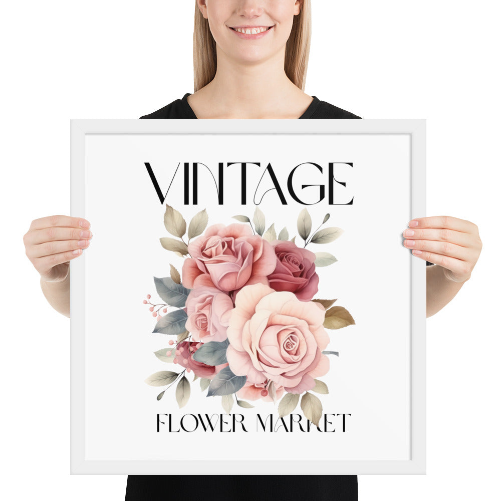 Person holding a framed artwork with floral design and text 'Vintage Flower Market'.