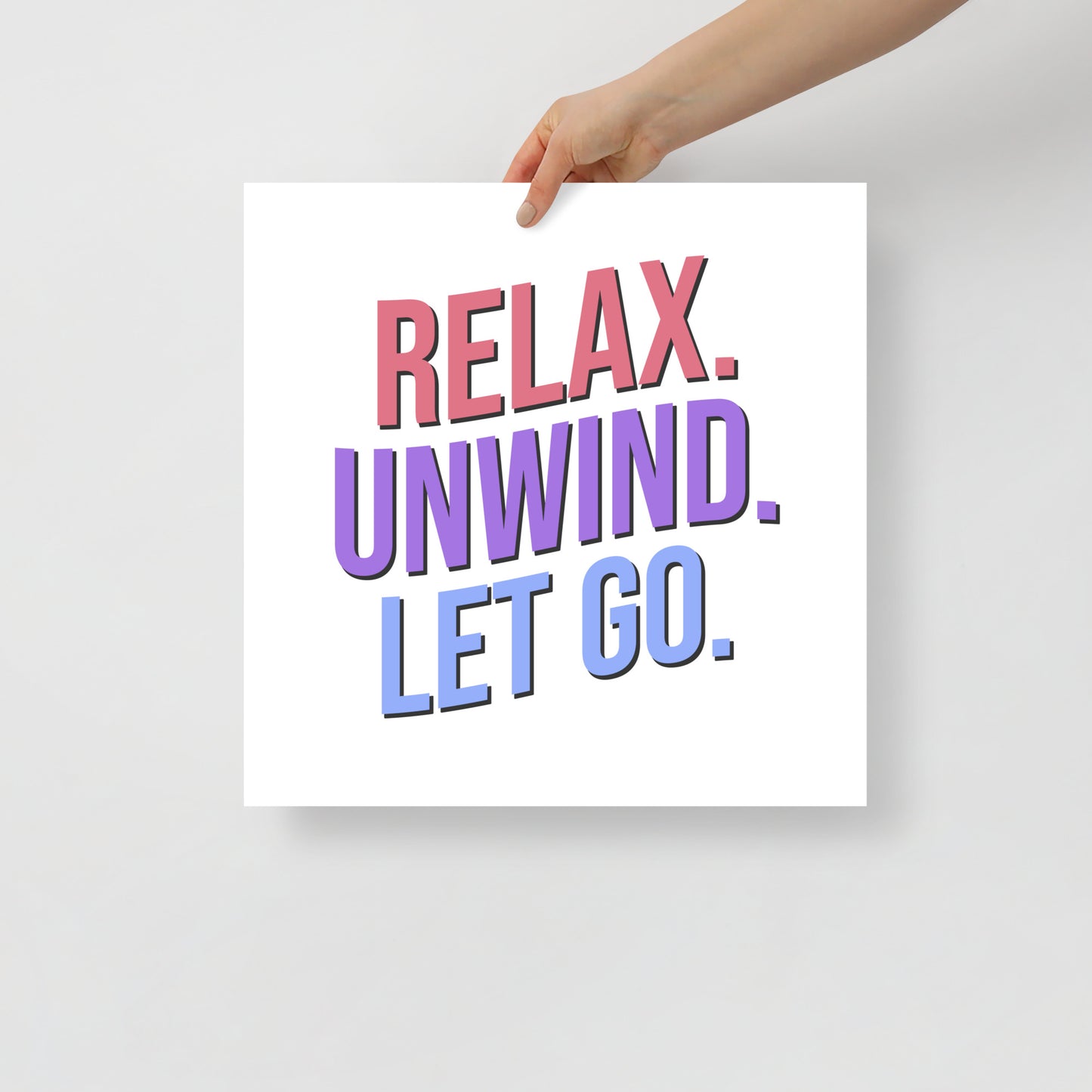Hand holding a sign with 'Relax. Unwind. Let Go.' text on a plain background