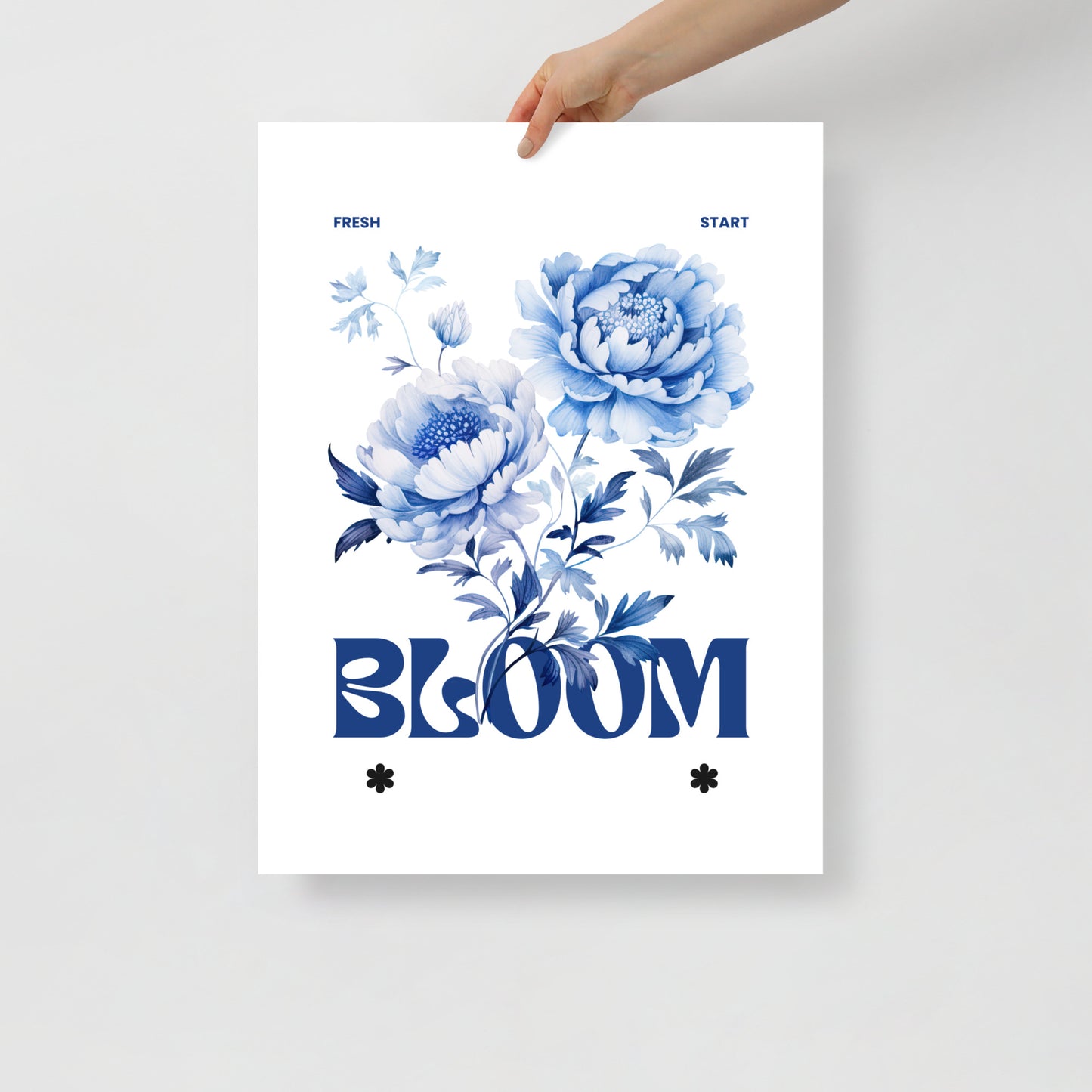 Poster with blue floral design and the word 'BLOOM' held by a hand on a light gray background