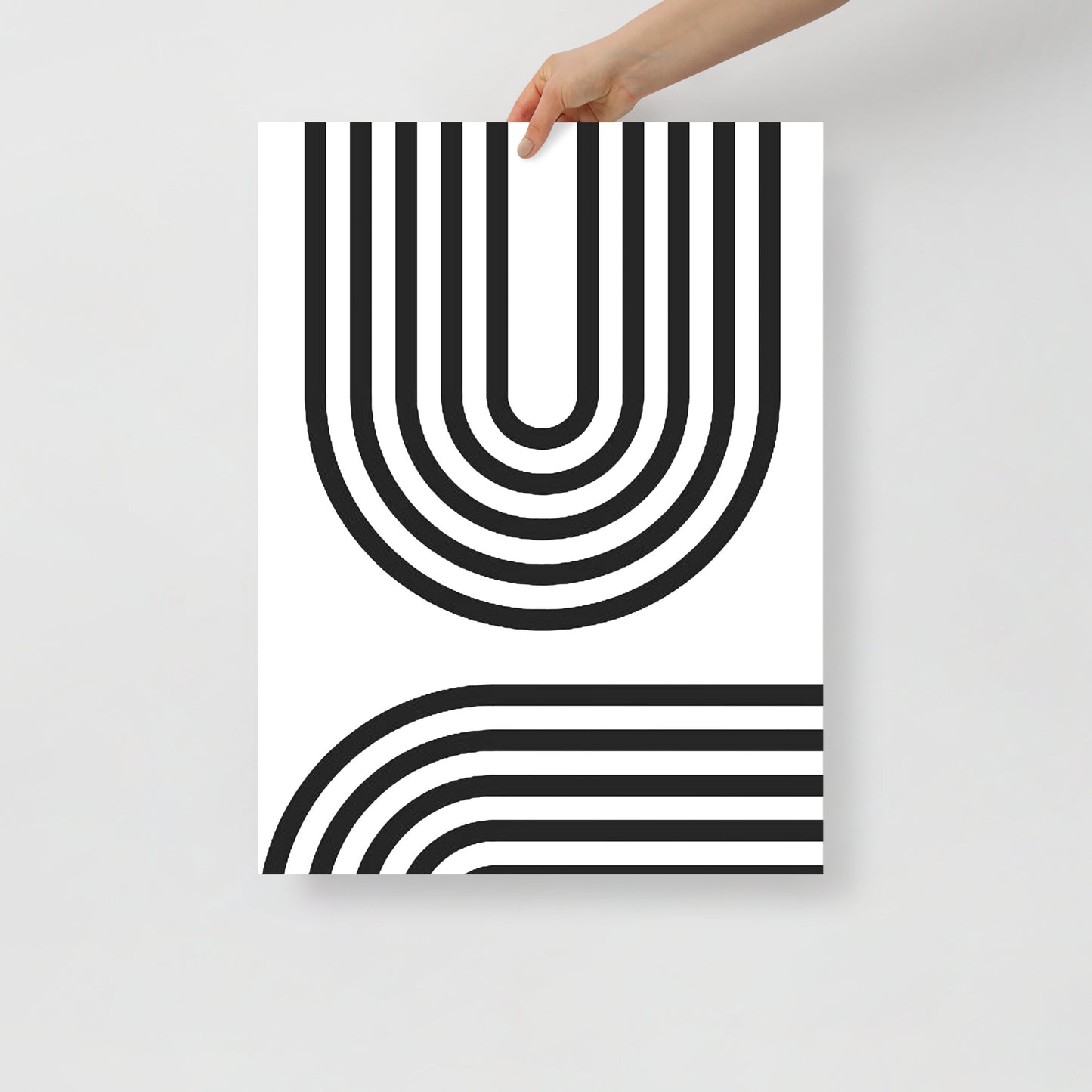 Poster with black and white geometric design held by a hand on a light gray background
