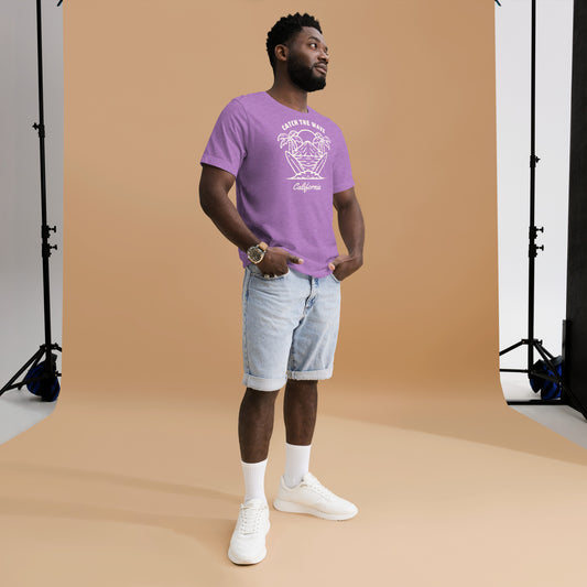 Man wearing a purple t-shirt with a logo and light blue shorts standing against a brown backdrop.