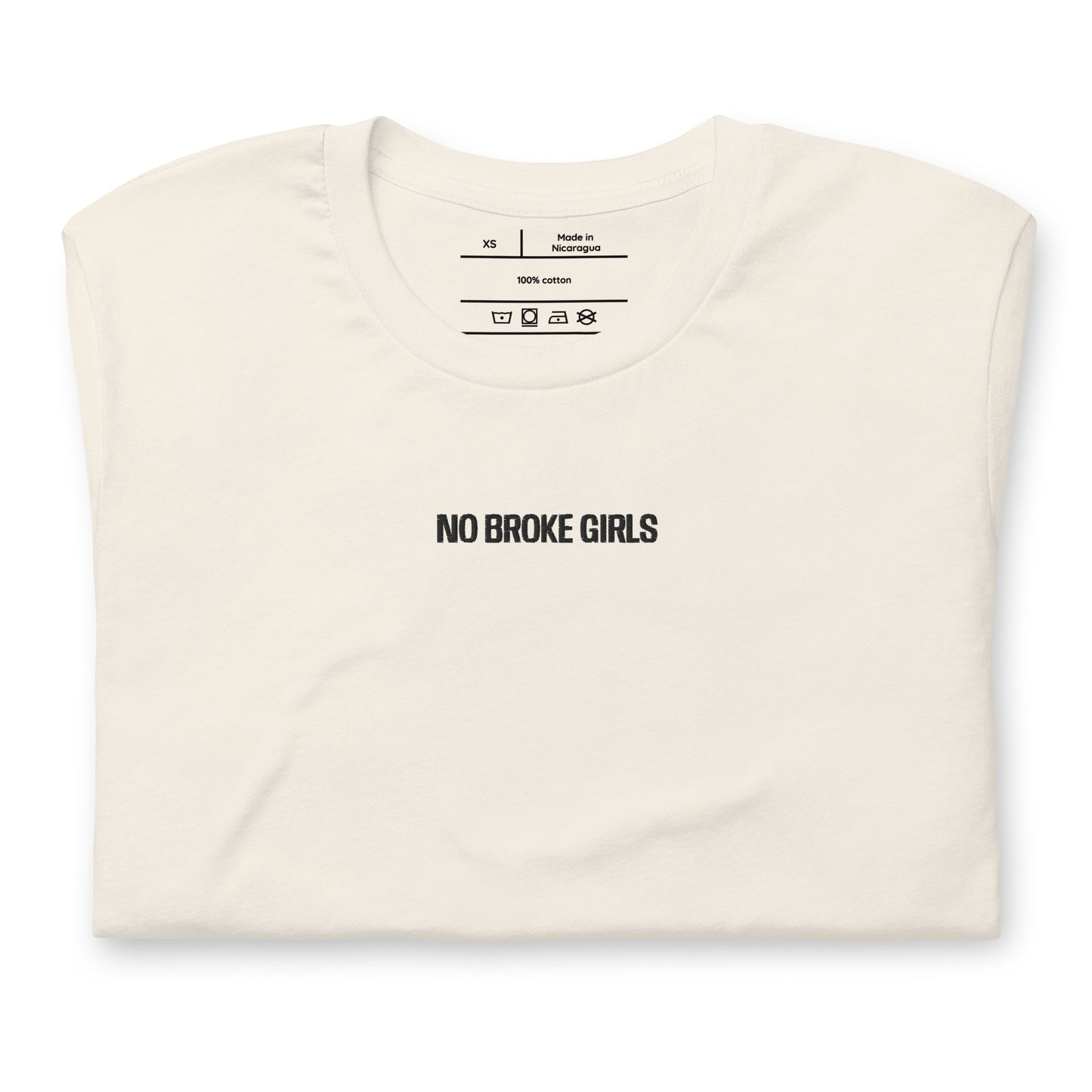 Folded cream t-shirt with 'NO BROKE GIRLS' text on a white background